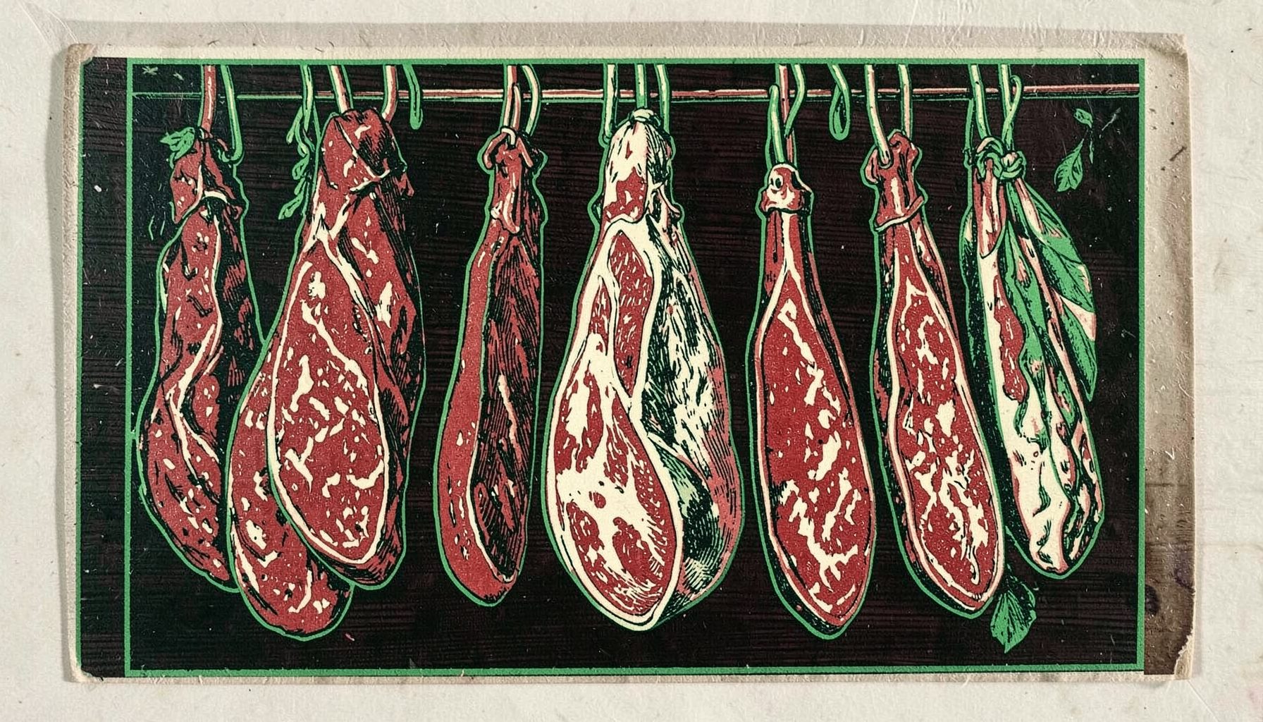 Saucissons et jambons secs suspendus, teintes rouges brique et blanc ivoire, sur fond de bois sombre