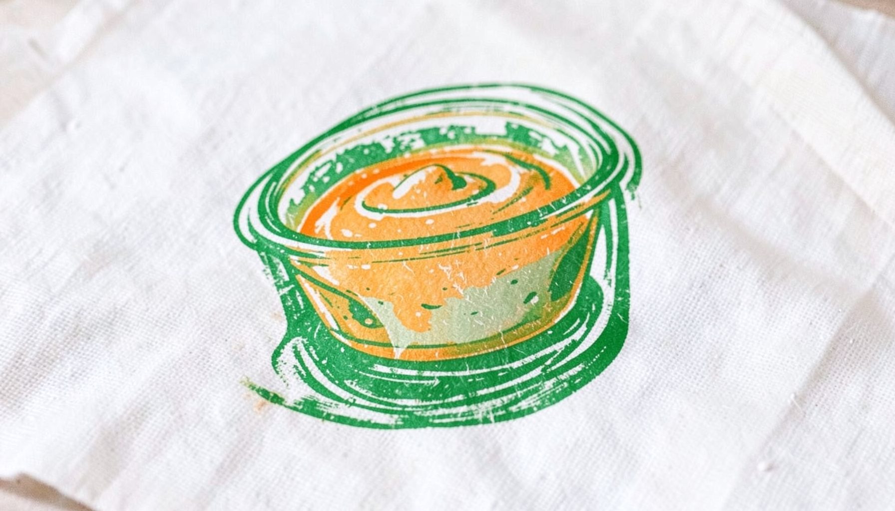 Petits pots en verre de purée et compote pour bébé, teintes douces orange et vert pâle, sur un linge blanc