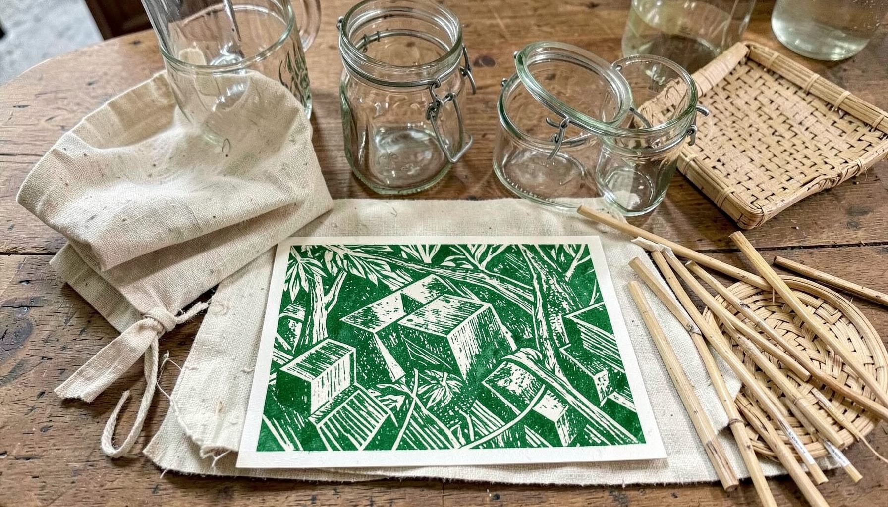 Sacs en tissu réutilisables, bocaux en verre de tailles variées, pailles en inox et couverts en bambou disposés sur une table en bois